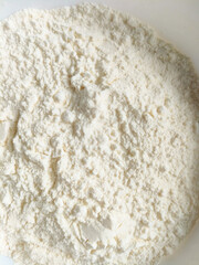 White flour in a clean white bowl on a white background. Minimalist cooking ingredient for baking and culinary use.