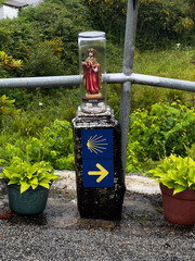 yellow arrow and shell signs under a statue of Saint James under a glass tube on the pilgrimage along the road to Santiago in Portugal, Caminho Portugues