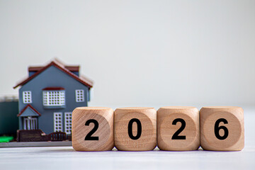 Financial coins stacked with wooden cubes of the year 2026 on a natural background. Piggy bank. New Year 2026 is about finances and saving money.