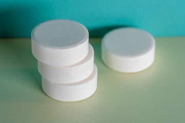 Four white medicine tablets laying isolated on green and blue pastel background as macro 2