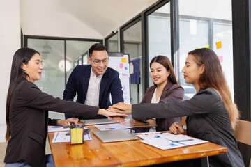 Group of Asian businesspeople Join hands and work together as a team in modern office, Business startup and company strategy planning concept.