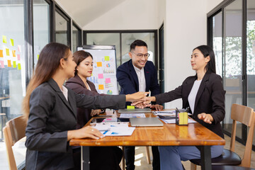 Group of Asian businesspeople Join hands and work together as a team in modern office, Business startup and company strategy planning concept.