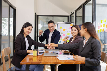 Group of Asian businesspeople Join hands and work together as a team in modern office, Business startup and company strategy planning concept.