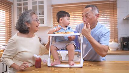 Happy Asian parents enjoying mealtime with their toddler in the kitchen