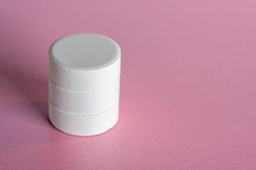 Ordered staple of four white medicine tablets laying isolated on pink pastel background as macro 1