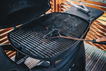 Cleaning outdoor barbecue grill. Close-up of a person cleaning a bbq grill with a wire brush with rising smoke.