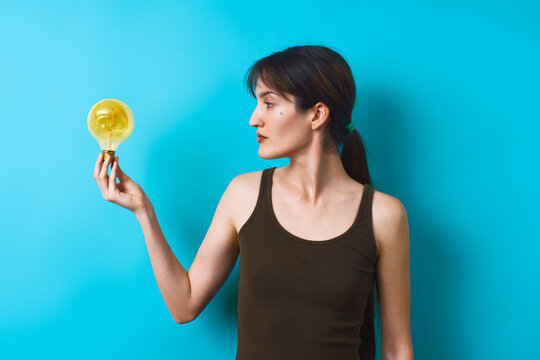 Woman holding light bulb on bright blue background