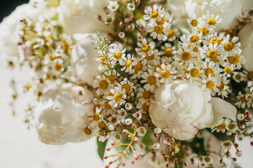 White blossoms with daisies and peonies in soft light