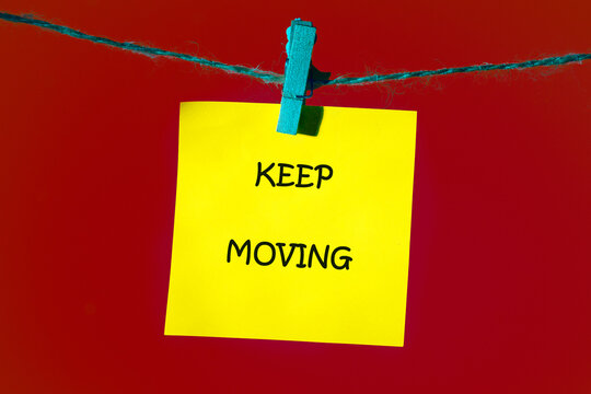 Business, motivation and keep moving concept. KEEP MOVING words written on a bright yellow note, which is attached to the shoelace with a blue clothespin on a bright red background