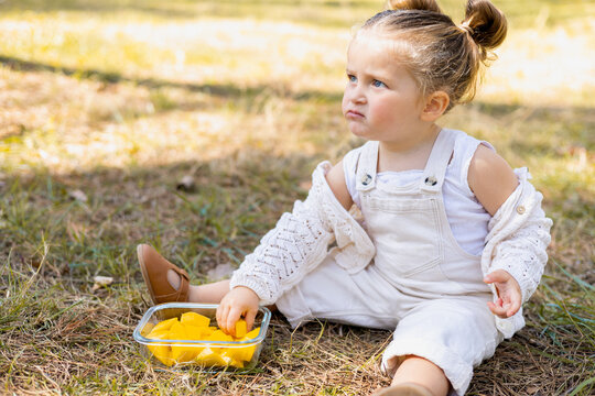 Child enjoying outdoor snack with fresh fruit