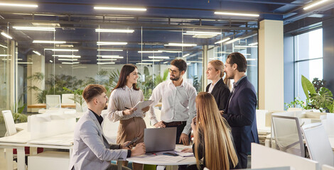 Smart business people using laptop during corporate meeting, work in small group, trying to solve financial problems of company, have brainstroming session and sharing good ideas