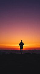 Obraz premium Runner’s Silhouette Against Dramatic Sunset on Hilltop