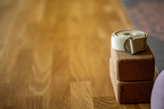 a yoga block and a yoga belt wit space around on a wooden ground