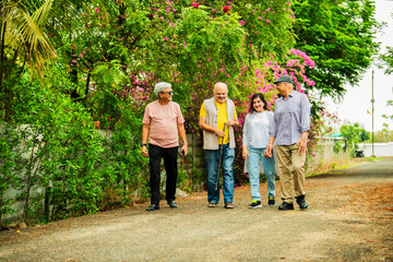 Fototapeta premium Elderly Indian friends reconnect in nature, enjoying laughter, memories, lush green surroundings