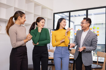 Obraz premium Group of Asian businesspeople talking together and brainstorm standing in modern office, Business startup and company strategy planning concept.