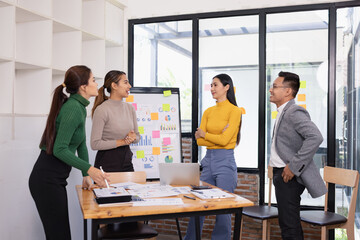 Fototapeta premium Group of Asian businesspeople talking together and brainstorm standing in modern office, Business startup and company strategy planning concept.