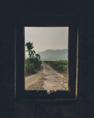 View through the window of an abandoned house by a lake in Koraput, Odisha, India in November 2024....