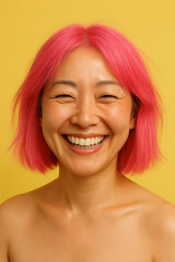 Smiling Asian woman with short pink hair against a yellow background. She has a joyful expression and is wearing no top, showcasing her natural beauty.