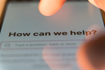 Close-up of a smartphone screen showing a support page with the text How can we help under a user...