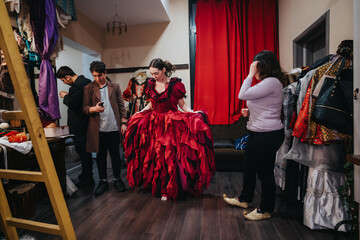 Group of young performers in a theater dressing room as they prepare for their performance,...