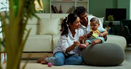 Parents sitting with baby boy while sitting on floor near sofa in modern living room, showcasing Indian family bonding, love, parenting, parenthood, emotional care, happy lifestyle, and cozy moments - Powered by Adobe