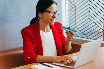 Businesswoman using a smartphone and laptop in a modern office setting