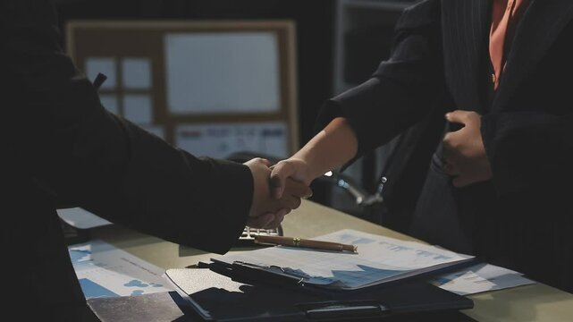 Business people shaking hands at meeting while theirs colleagues clapping and applauding. Group of unknown businessmen and women in modern white office. Success teamwork, partnership and handshake