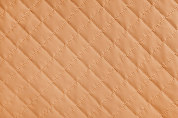 Obraz premium Checkered, diamond stitching pattern, orange quilted fabric background. Blanket or puffer jacket, stitch rhombus texture close up, macro. Wallpaper, backdrop.