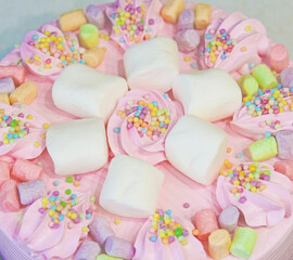 Arranged cream marshmallow cake for festive event. Sweet food, perfect for children's parties. Details of dessert table. Wedding accessories in a soft pink presentation. Decoration wedding party
