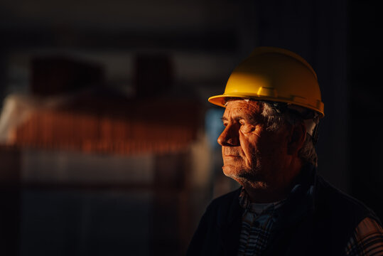 Senior construction worker wearing hardhat contemplating project progress