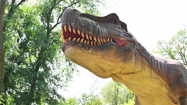 Living statue of Tyrannosaurus in forest on grass. Dinosaur park doll, entertainment for children, prehistoric creature, museum 