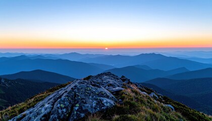 Rocky peak overlooks layered blue mountains as the sun crests the horizon