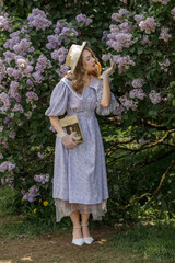 A beautiful young blonde woman, against a background of blooming lilacs, in a lilac vintage dress....