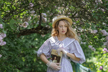A beautiful young blonde woman, against a background of blooming lilacs, in a lilac vintage dress....