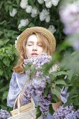 A beautiful young blonde woman, against a background of blooming lilacs, in a lilac vintage dress. A walk in the park.