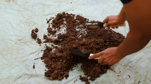 gardener mixing cow dung fertilizer at plastic sheet at outdoor