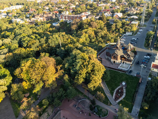 Aerial drone view of a wooden church next to a playground in a lush green city park