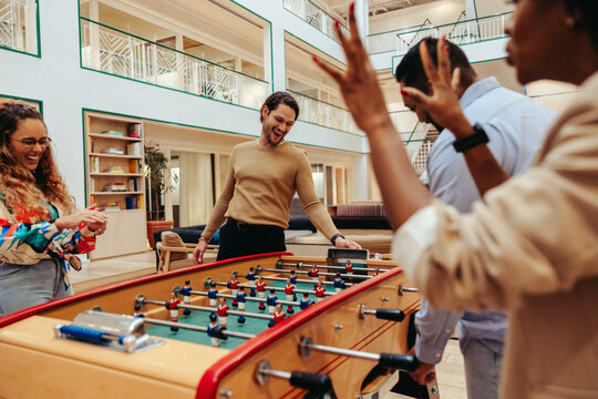 Group of colleagues playing foosball and enjoying a competitive team-building activity
