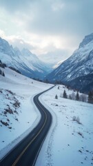 Snow covered mountain range with a winding road in the middle. The road is surrounded by trees and the mountains are covered in snow. The scene is peaceful and serene