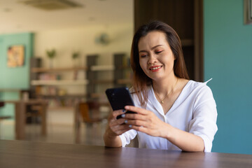 Woman sitting in library using phone