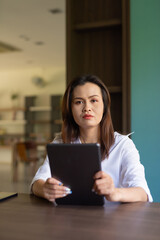 Fototapeta premium Woman reading from tablet computer in library