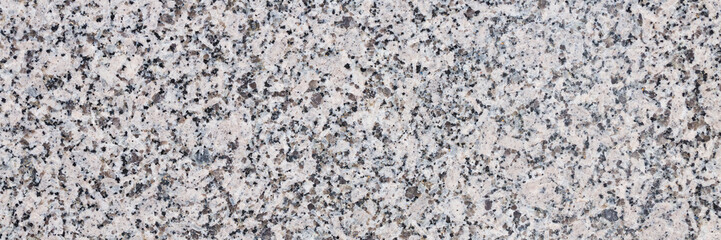 Granite texture. Natural granite with a grainy pattern. Stone background. Solid rough surface of rock. Durable construction and decoration material. Close-up.
