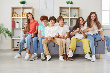 Group of happy and diverse students or friends sits together on a couch, enjoying leisure time and...