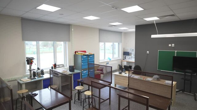 Well-illuminated classroom shows individual workstations with clear barriers. Spacious layout and ample lighting promote focused learning