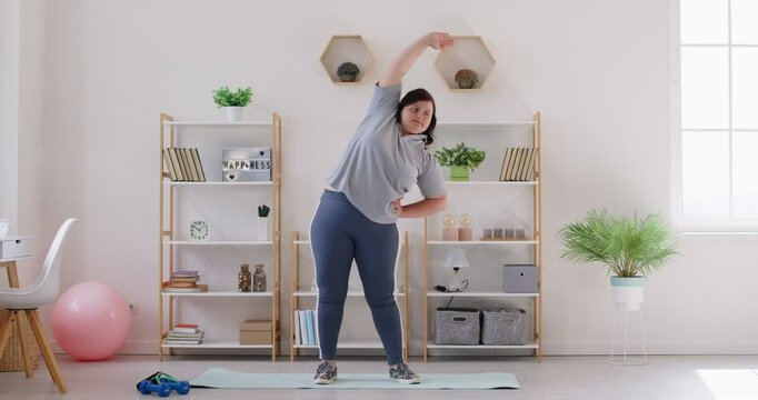 Obese woman workouting at home doing side bend exercise fitness, trying to practice in living room, chubby overweight plus size big fat fit lady motivated girl planning weight loss, improving body