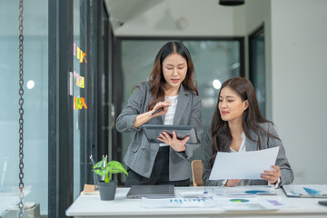 Group of happy Asian business people having a meeting at the office. Two women working together using modern laptops.