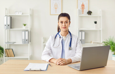 Portrait of a serious female doctor or nurse sitting at the desk in a hospital, clinic office. The...