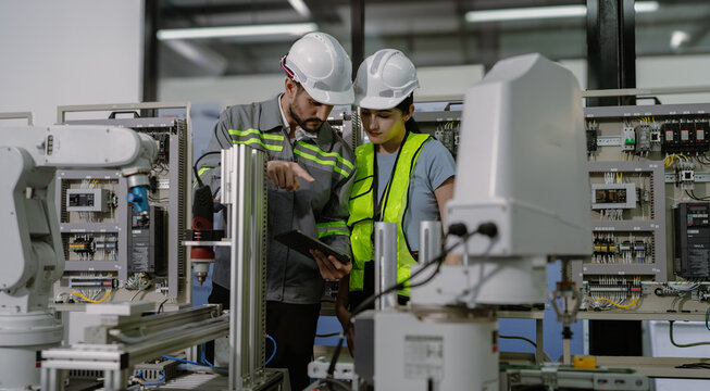 Group of hispanic people working on robot programming in robotic and electronic engineering laboratory. Latino engineer team learning and research automated machine with intelligent mechanical control