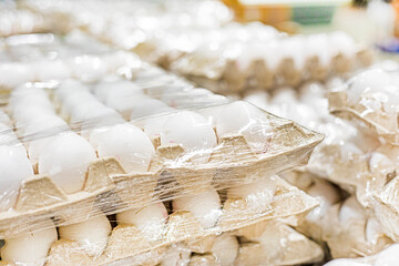 white chicken eggs in cardboard containers in a supermarket. Economic crisis