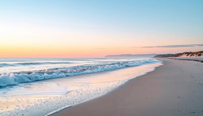 Fototapeta premium Coastal scene with foamy waves, sandy beach, blue sky at dawn/dusk